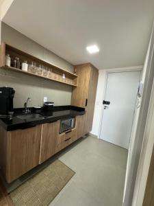 a kitchen with wooden cabinets and a sink and a door at Studio Aconchegante in Poços de Caldas