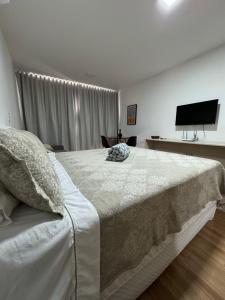 a bedroom with a large bed and a flat screen tv at Studio Aconchegante in Poços de Caldas