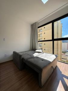 a large bed in a room with a large window at Studio Aconchegante in Poços de Caldas