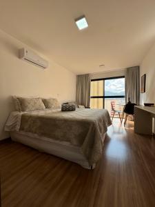 a bedroom with a large bed and a large window at Studio Aconchegante in Poços de Caldas