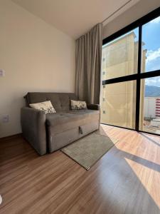a living room with a couch and a large window at Studio Aconchegante in Poços de Caldas