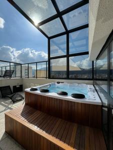 a hot tub in the middle of a room with windows at Studio Aconchegante in Poços de Caldas