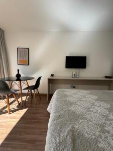 a bedroom with a bed and a table and a tv at Studio Aconchegante in Poços de Caldas