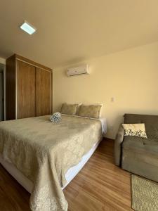 a bedroom with a large bed and a couch at Studio Aconchegante in Poços de Caldas