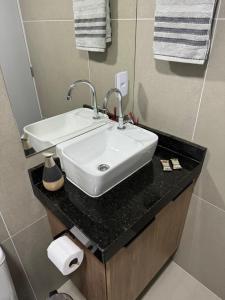 a bathroom with a white sink on a black counter at Studio Aconchegante in Poços de Caldas