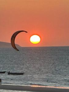 a person flying a kite on the beach at sunset at Belíssima casa no Preá in Cruz
