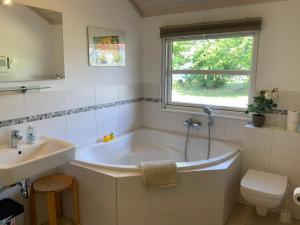 ein Badezimmer mit Badewanne und Waschbecken und einem Fenster in der Unterkunft Ferienhaus Villa Sun Rügen in Vaschvitz + 34 Fotos