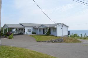 uma casa branca com o oceano ao fundo em Hôtel Maison Blanche em New Carlisle