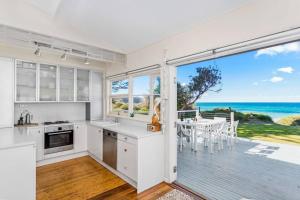 a kitchen with white cabinets and a view of the ocean at The Mook on Mollymook Beach in Mollymook