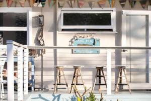 a patio with stools in front of a white house at The Mook on Mollymook Beach in Mollymook