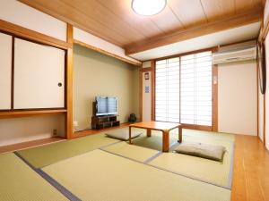 a living room with a table and a tv at Kawaguchiko Inn Yesterday in Fujikawaguchiko