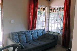 a living room with a blue couch in front of windows at Casa temporada na praia Joia do Atlântico - Ilhéus - Ba in Ilhéus