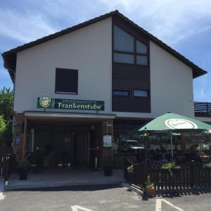 a white building with a green umbrella in front of it at Frankenstube in Eichelsdorf