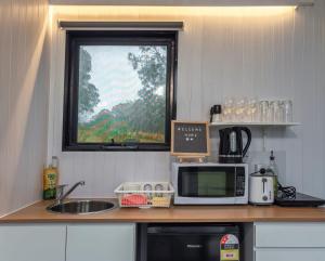 a kitchen with a microwave and a sink and a window at The Fog Getaway by Tiny Away in Boolambayte