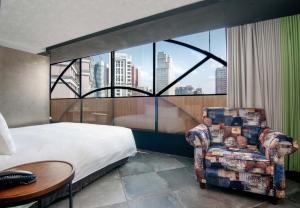 a hotel room with a bed and a chair and a window at Calligraphy Greenway Hotel in Taichung