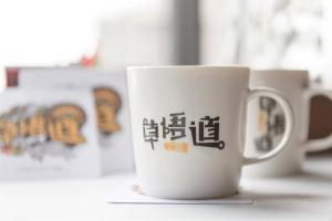 a white coffee mug with chinese writing on it at Calligraphy Greenway Hotel in Taichung