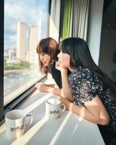 two women sitting on a train looking out a window at Calligraphy Greenway Hotel in Taichung
