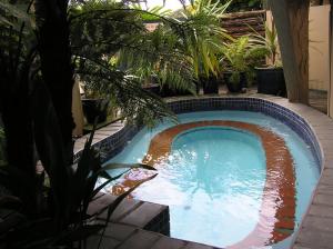 - une piscine dans une cour ornée de plantes dans l'établissement Ambassador Thermal Motel, à Rotorua
