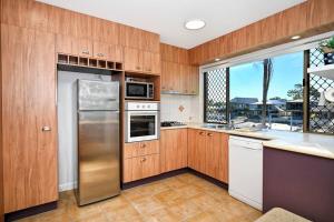 una cucina con armadi in legno e frigorifero in acciaio inossidabile di Mooloolaba Tranquil Hideaway a Mooloolaba