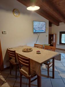 a dining room table with chairs and a tv on the wall at Splendida Mansarda, aria condizionata "ALLE MURA DEL CASTELLO 2 Stefano e Paola Marchesini" in Gorizia