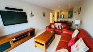 Il comprend un salon doté d'un canapé rouge et d'une télévision à écran plat. dans l'établissement Sunrise Ocean Views Retreat Cowes Phillip Island, à Cowes