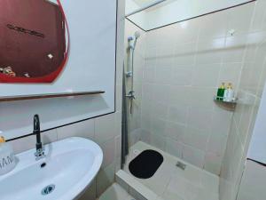 een witte badkamer met een wastafel en een douche bij Baguio Condotel - City Center in Baguio