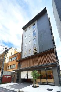 a building on a street with a tree in front of it at THE POCKET HOTEL Kyoto Shijo Karasuma in Kyoto