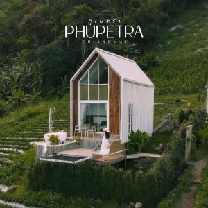 a woman sitting on a bench in front of a tiny house at Phupetra ภูเปตรา in Ban Thung Phan Ha