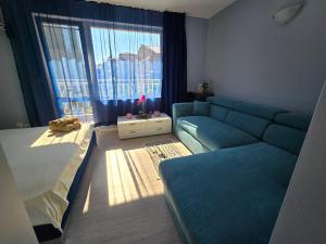 a living room with a couch and a bed and a window at Квартири СЪН in Nesebar