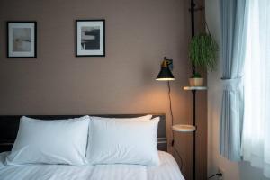 a bedroom with a bed with white pillows and a lamp at Norwegian Wood in Kita-sanjō +69 photos