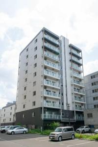 a tall building with cars parked in a parking lot at Norwegian Wood in Kita-sanjō