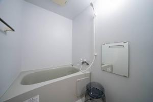 a white bathroom with a tub and a mirror at Norwegian Wood in Kita-sanjō