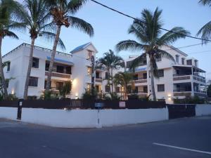 un edificio con palme di fronte a una strada di Sweet Beach Apt-Pool, Terrace, Ground Floor, few steps from beach! a Flic-en-Flac