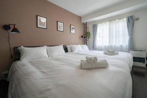 a large white bed with two towels on it at Norwegian Wood in Kita-sanjō