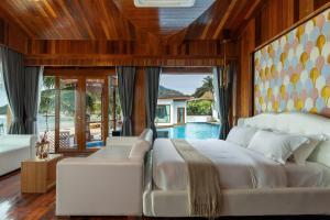 ein Schlafzimmer mit einem weißen Bett und einem Pool in der Unterkunft Hotel Villa AoKhanom Beachfront in Khanom + 37 Fotos