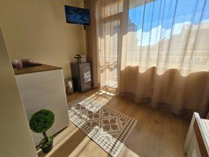 a living room with a window and a door with a rug at Квартири СЪН in Nesebar