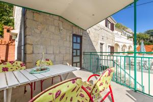 un patio con tavolo e sedie su un balcone di Renovated Old Stone House a Lokva Rogoznica