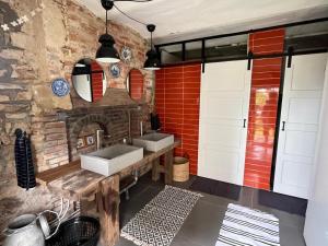 ein Badezimmer mit zwei Waschbecken und einer Ziegelwand in der Unterkunft Le Brasseur Logements - Tents in Saint-Caprais