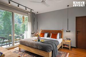 Un dormitorio con una cama grande y un balcón. en StayVista at Kaira with Music Speaker & Heater, en Bhowāli