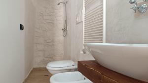 a white bathroom with a sink and a toilet at Dimora di Ponente in Ostuni