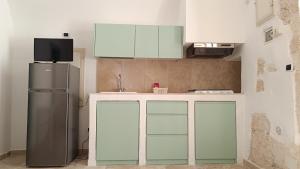 a kitchen with white cabinets and a refrigerator at Dimora di Ponente in Ostuni +12 photos