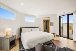 ein Schlafzimmer mit einem großen weißen Bett und einem Stuhl in der Unterkunft Malibu Sand Carbon Beach Suites in Malibu + 143 Fotos