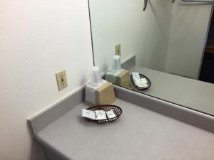 a bathroom counter with a mirror and two complimentary toothbrushes at Sunshine Motel in Fife