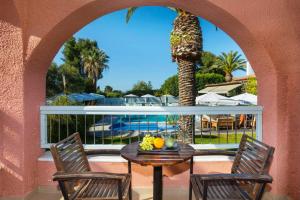 a patio with a table and chairs and a palm tree at Hotel Hanioti Village Spa in Hanioti