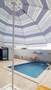 DjerbaにあるVilla avec piscine, 3 suites, 6lits, à 3min de la plageの青と白の傘が付いたプール