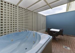 bañera grande en una habitación con mesa en Geneva Motor Lodge, en Rotorua 45 fotos más