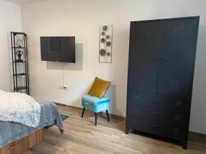 a bedroom with a large black dresser and a blue chair at Alte Schreinerei in Bielefeld