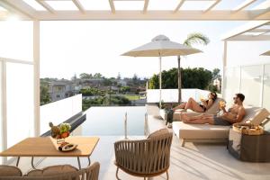 two people sitting on a couch on the roof of a house at Thimios Suites Adults Only in Acharavi