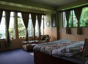 a bedroom with a bed and a chair and windows at Adrija Luxury homes, Kanchenjunga View, 2000 sqft in Darjeeling
