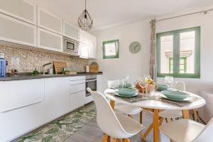 Una cocina con gabinetes blancos y una mesa y sillas. en La Flor Beach, en Puerto de Mogán